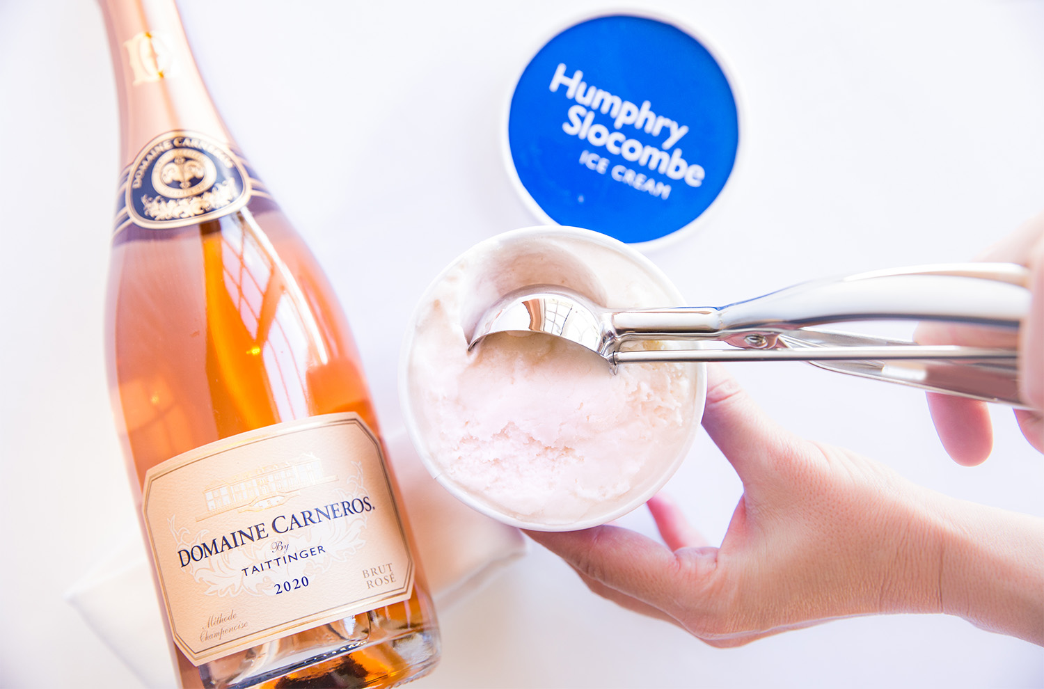 Ice cream pint open with scooper and bottle of sparkling rose wine