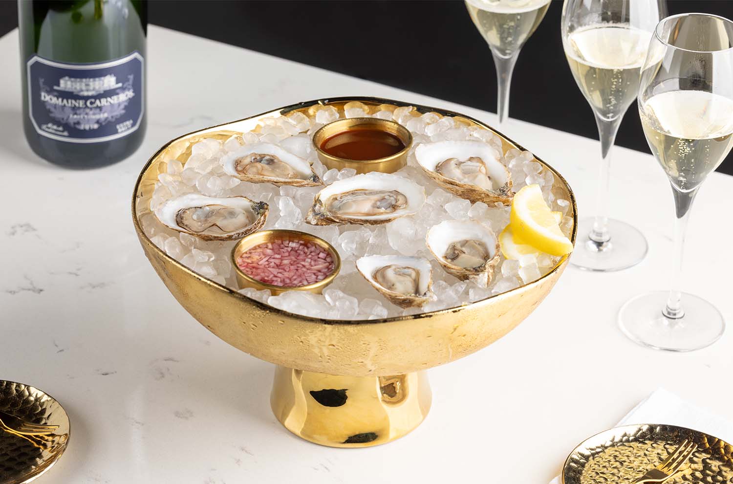 plate of oysters on ice and glasses of sparkling wine