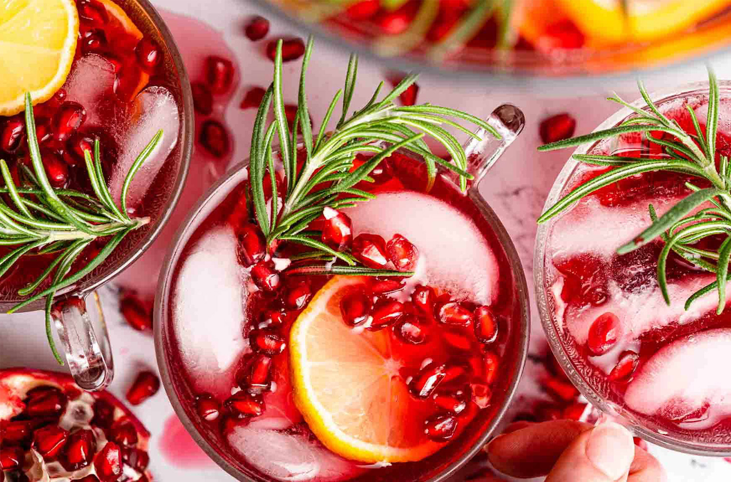 Glass of cranberry-pomegranate punch from above with orange slice and rosemary sprig