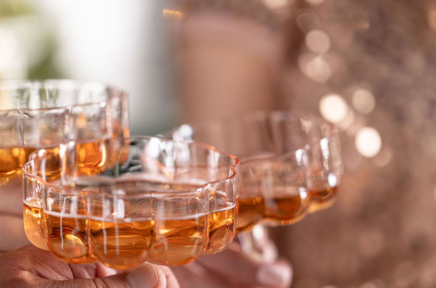 three pink coupes toasting with sparkly dress background